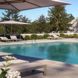 resort style pool with seating trees and a building behind it